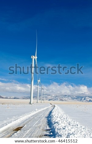 A snow covered road to a rural wind farm.