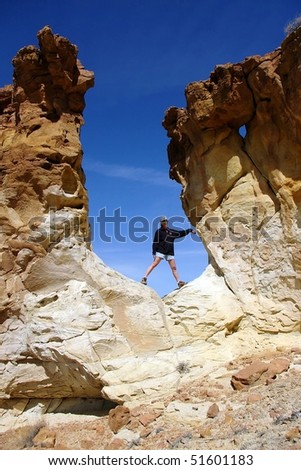 A woman stands in an opening in a sandstone cliff in the desert.