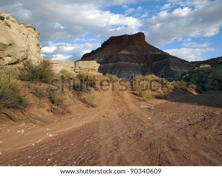 A dirt road passes through a sandy, desert wash.