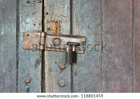 Old style wooden door locked with hasp and key