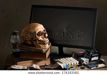 Still life photography, Human skull with mainboard, cracked monitor and old reference book in computer technician concept
