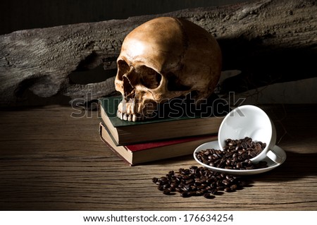 still life photography, coffee beans in white coffee cup with skull and old book on old wood background