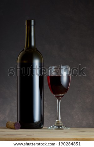 Wine Bottle, glass and cork on wooden table with art dark background