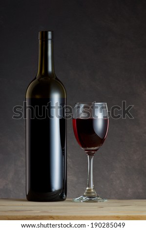 Wine Bottle and glass on wooden table with art dark background