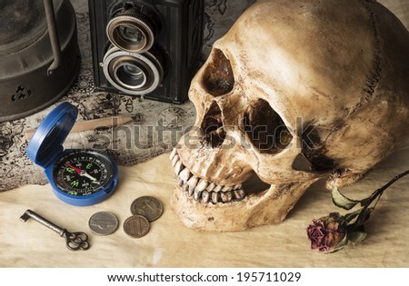Still life photography on skull, compass, camera, coin and key in traveler concept