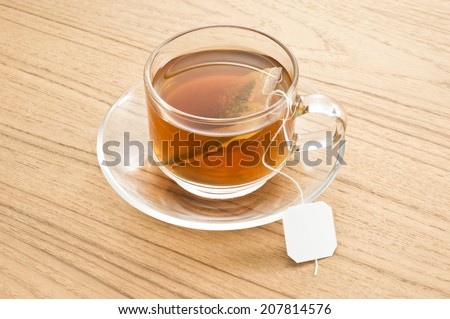 tea in glass cup and saucer with blank label teabag on wood  table