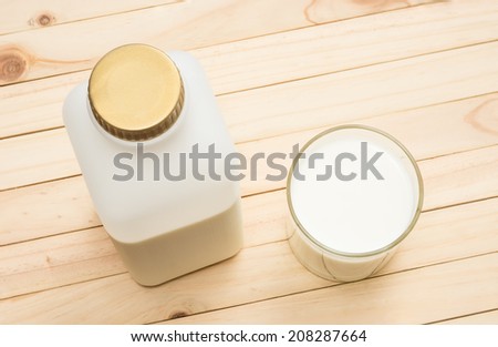 plastic milk bottle and milk in glass on pine wood plank