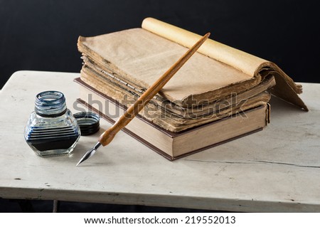 still life photography, opening old book on old table with quill pen and inkwell