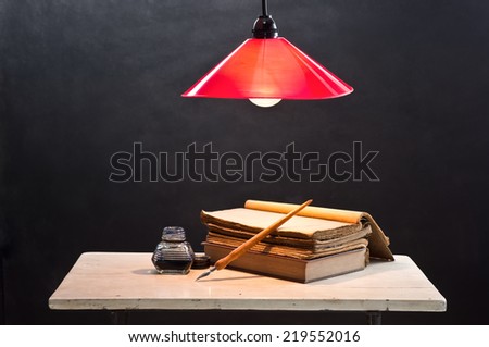 still life photography, opening old book on old table with quill pen inkwell and lighted lamp