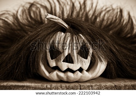 halloween pumpkin, orange pumpkin on old wood carving to evil face is wearing wig in sepia color tone