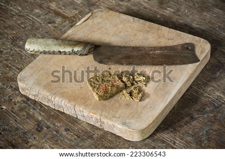 dry hashish piece on old chopping block with old knife