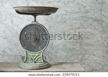 old weighing machine on wood table with concrete plaster background
