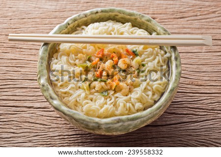 cooked hot and sour flavor instant noodle with ingredient in ceramic bowl with bamboo chopsticks