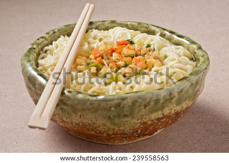 cooked hot and sour flavor instant noodle with ingredient in ceramic bowl with bamboo chopsticks