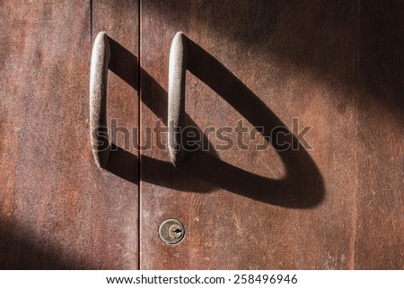 the long shadow of rusty handle and key hold of old wood cupboard