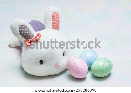 Cute easter bunny with colorful glitter easter eggs on soft colorful background