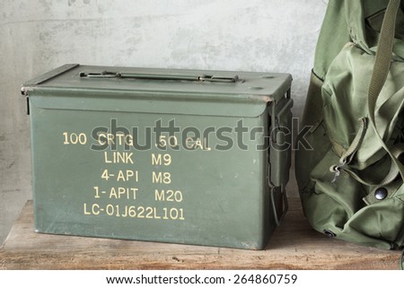 still life photography : Old and dusty bullet box ( ammo crate ) with part of Military backpack on old wood