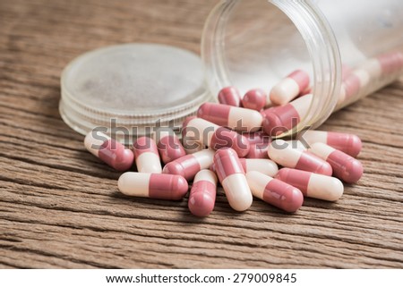 pills capsules with old plastic bottle on wood