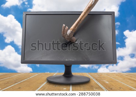 destroy the old computer monitor with hammer on wood plank with cloud and blue sky at background