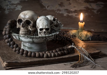 still life photography : skull and rosary in ceramic offering dish on old book in exorcist concept