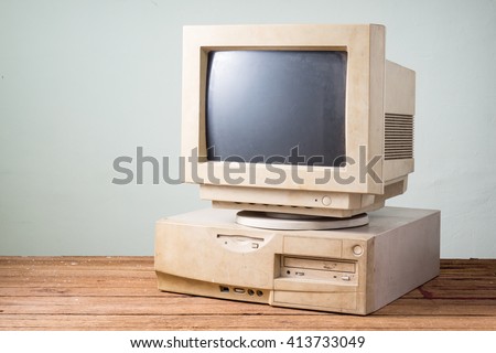 old and obsolete computer on old wood table with concrete wall background