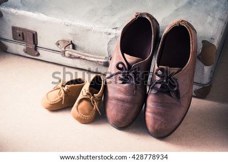 Old adult leather shoes and kid shoes with old suitcase, Travel together or father\'s day concept