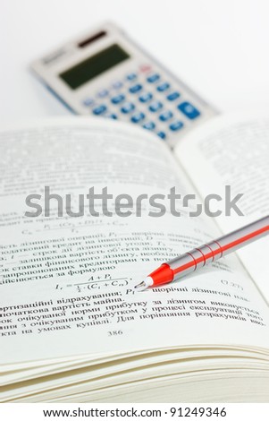 Opened textbook on economics with pen and calculator