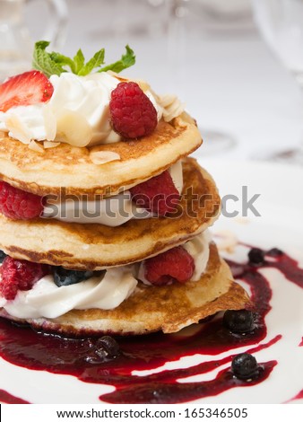 Crumpets with raspberry sauce , whipped curd cheese and roasted almonds