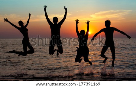 Silhouette Of Jumping People On Sunset Background