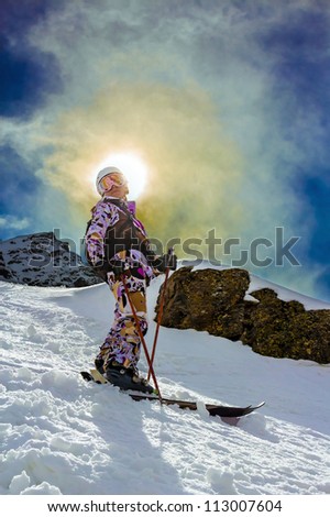 Woman skiing in the big mountains against the sky and the sun backlit