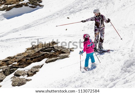 Mother and daughter on skis in soft snow on a sunny day in the mountains planned route of descent