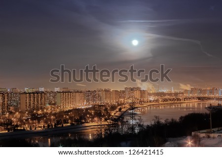 Full moon in the night sky above the glowing city