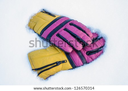 Multicolored leather ski gloves on white snow