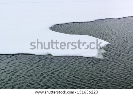 Sinuous edge of the ice field in the snow and the area of open water