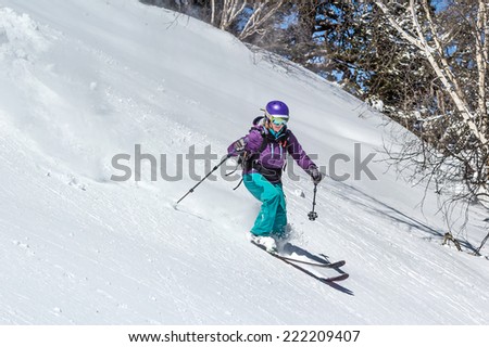 Female skier in deep snow. Off-piste skiing in soft snow on a cold sunny day in the forest zone