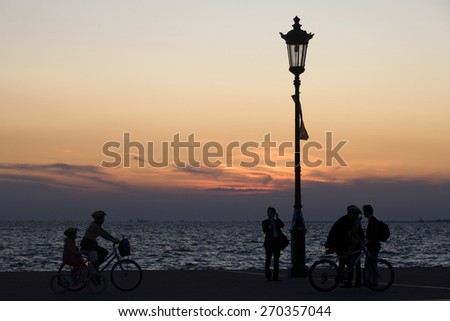 THESSALONIKI, GREECE - SEPTEMBER 22, 2009: Silhouettes of people enjoying a walk by the seaside of the town during sunset.