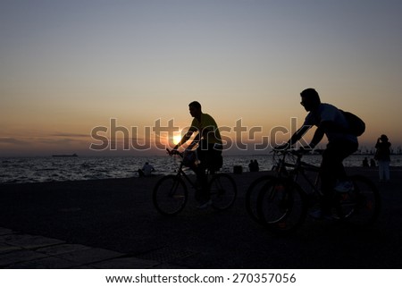 THESSALONIKI, GREECE - SEPTEMBER 22, 2009: Silhouettes of people enjoying a walk by the seaside of the town during sunset.