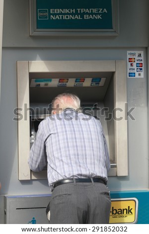 GREECE, Thessaloniki JUNE 29, 2015: An old man uses a cash machine outside a closed national bank. Greek banks will stay closed for six days, and capital controls will be imposed when they reopen.