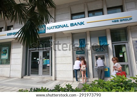 GREECE, Thessaloniki JUNE 29, 2015: Citizens use cash machines outside a closed national bank. Greek banks will stay closed for six days, and capital controls will be imposed when they reopen.