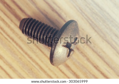Old used screw on a wooden bench. Image cross processed for vintage feeling.