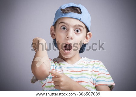 Scared little boy showing band aid in hand