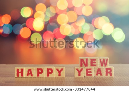 Christmas concept with Happy New Year wish formed on wooden blocks and defocused bokeh Christmas lights background