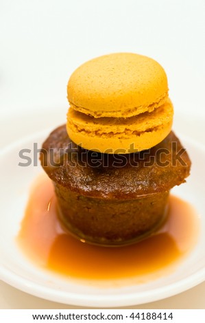 Sticky pudding dessert in a plate with caramel sauce with marzipan decoration.