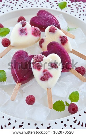 Frozen popsicle in heart-shape with fresh raspberries