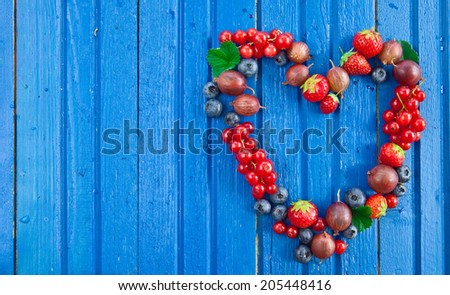 Blue wooden background with fresh summer berries