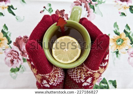 Hands in knitted gloves holding a mug with a hot beverage
