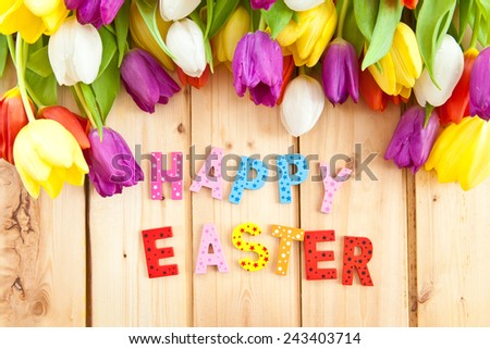 Happy Easter written in multicolored letters and fresh tulips
