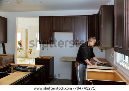 Carpenter installing cabinets and counter top in a kitchen. and partially installed
