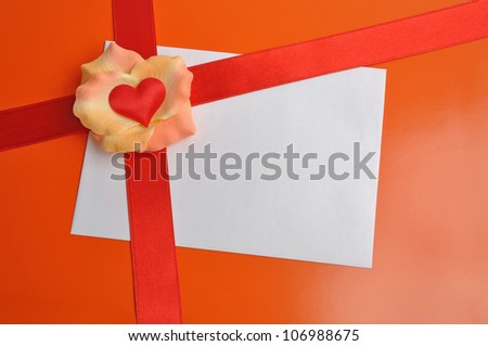 White card with rose petals. Postcard with heart on the orange background. Letter with a red ribbon.