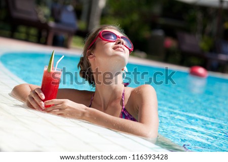 beautiful girl in sunglasses with fresh watermelon juice in luxury pool